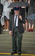 1 August 2013; Dan Murphy, from Dungarvan, Co. Waterford, shelters under his umberella at the edge of the stand, before the Guinness European Breeders Fund Corrib Fillies Stakes. Galway Racing Festival, Ballybrit, Co. Galway. Picture credit: Barry Cregg / SPORTSFILE