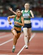 26 August 2023; Kelly McGrory of Ireland, left, takes the baton by Roisin Harrison while competing in the women's 4x400m relay during day eight of the World Athletics Championships at the National Athletics Centre in Budapest, Hungary. Photo by Sam Barnes/Sportsfile