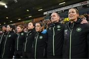 12 July 2024; Republic of Ireland staff, from right, assistant coach Emma Byrne, assistant coach Colin Healy, performance coach Ivi Casagrande, physiotherapist Angela Kenneally, team doctor Siobhan Forman, physiotherapist Susie Coffey, and masseuse Debbie Lester during the playing the the national anthem before 2025 UEFA Women's European Championship qualifying group A match between England and Republic of Ireland at Carrow Road in Norwich, England. Photo by Stephen McCarthy/Sportsfile