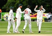 26 July 2024; Tanaka Chivhanga of Zimbabwe celebrates with teammates after taking the wicket of Ireland Captain Andrew Balbirne during day two of the Test Match between Ireland and Zimbabwe at Stormont in Belfast. Photo by Oliver McVeigh/Sportsfile