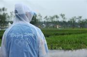 14 August 2008; A volunteer stands in the rain during heavy thunderstorms which forced the cancellation of all Rowing and Canoeing events for the day. The day's programme has been rescheduled for tomorrow, Friday. Beijing 2008 - Games of the XXIX Olympiad, Shunyi Olympic Rowing-Canoeing Park, Shunyi District, Beijing, China. Picture credit: Brendan Moran / SPORTSFILE