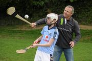 18 April 2011; All Black legend and Laureus Sport for Good Foundation goodwill ambassador Sean Fitzpatrick tries his hand at hurling with the help of Aideen Herlihy, from Blackrock, Dublin, a member of the Kilmacud Crokes U12 camogie team. Kilmacud Crokes GAA Club, Stillorgan, Co. Dublin. Picture credit: Stephen McCarthy / SPORTSFILE