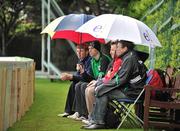 3 July 2012; Spectators shelter under umbrellas as the bad weather halted the start of play. ICC WCL Championship, Ireland v Afghanistan, Clontarf Cricket Club, Castle Avenue, Clontarf, Dublin. Picture credit: Barry Cregg / SPORTSFILE